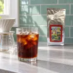Glass of iced black coffee beside a pour-over brewer and ANASU Armenia bag