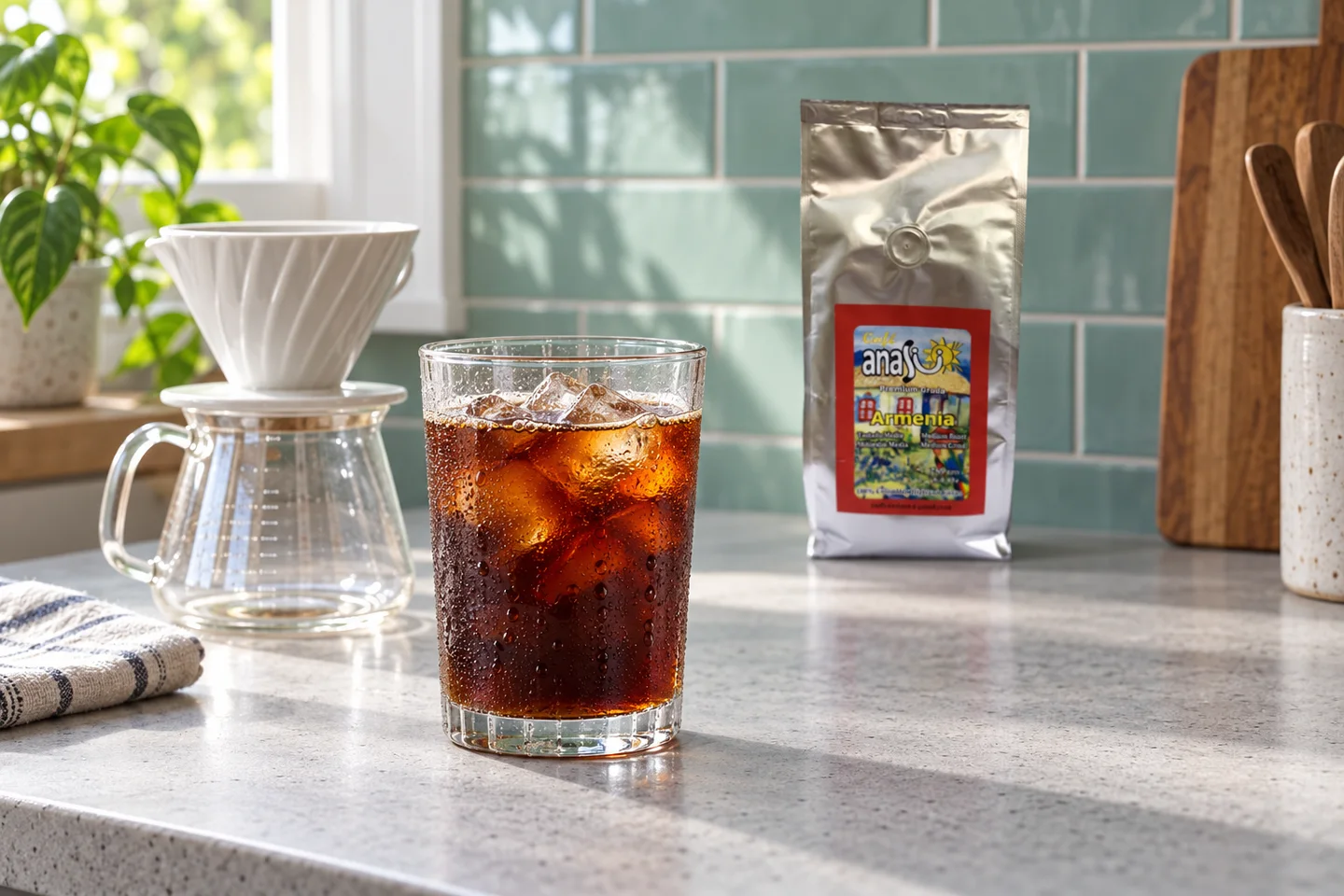 Glass of iced black coffee beside a pour-over brewer and ANASU Armenia bag
